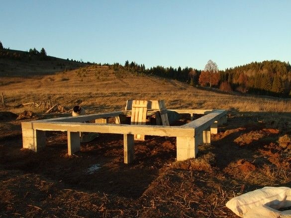 Fondation de colonne avec un grillage pour une maison en rondins et son achèvement